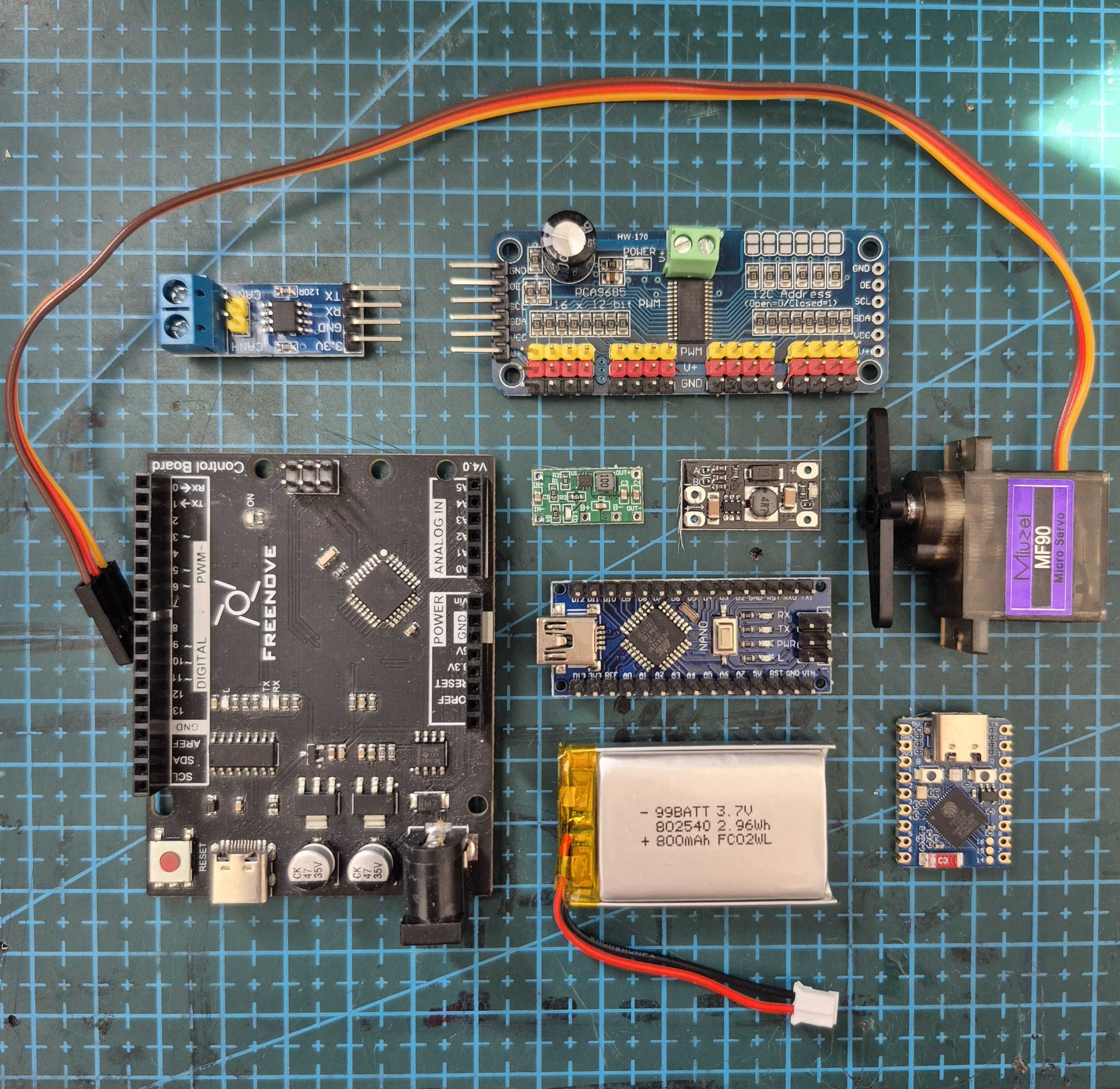 Microcontrollers, motor-control boards, a servo, and prototyping components arranged on a cutting mat